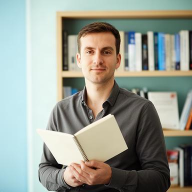 Grāmatvedības eksperts ar piezīmju grāmatu pie finanšu literatūras plaukta